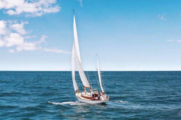 White two-masted sailboat under full canvas on deep blue water