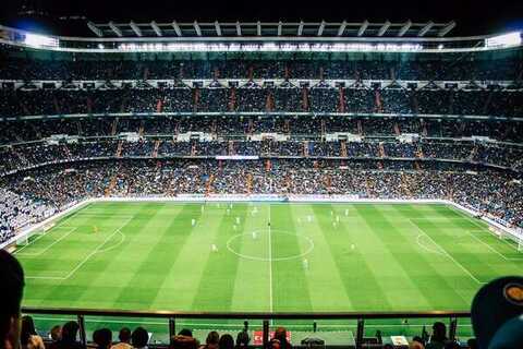 Packed soccer stadium under floodlights during a night match