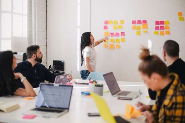 Facilitator pointing at sticky-note clusters while a team watches from a conference table
